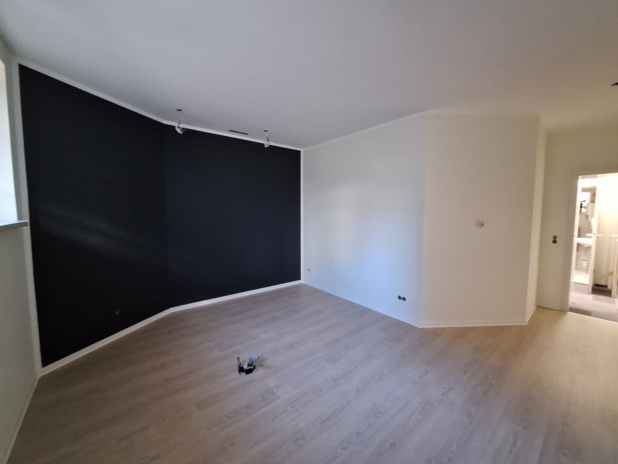 Wohnraum mit anthrazitfarbener Akzentwand und hellem Vinylboden
